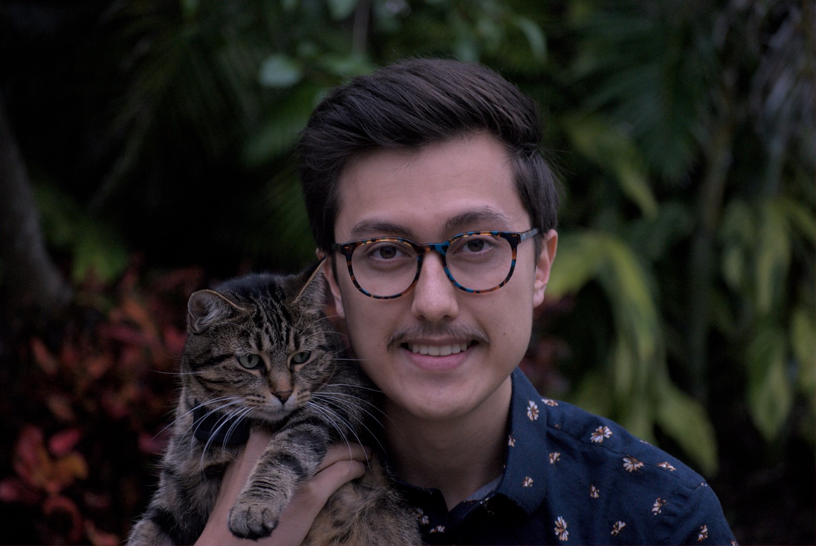 A young man holds a cat.